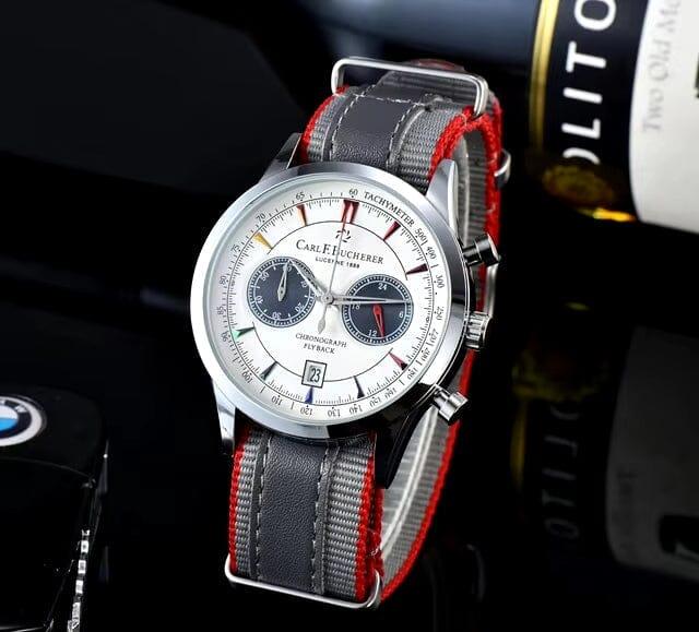 Luxury men's chronograph wristwatch with white dial, red accents, and grey leather strap on display