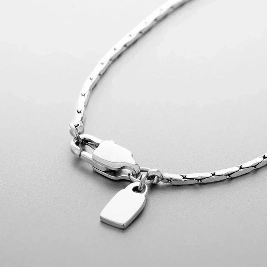 Auretier silver necklace with tag pendant and sleek chain on light grey background