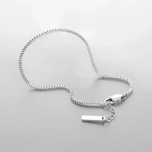 Auretier Milan silver box chain bracelet with tag charm on a light background.