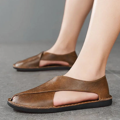 Brown leather sandals on feet, open toe design, Auretier style, gray floor background