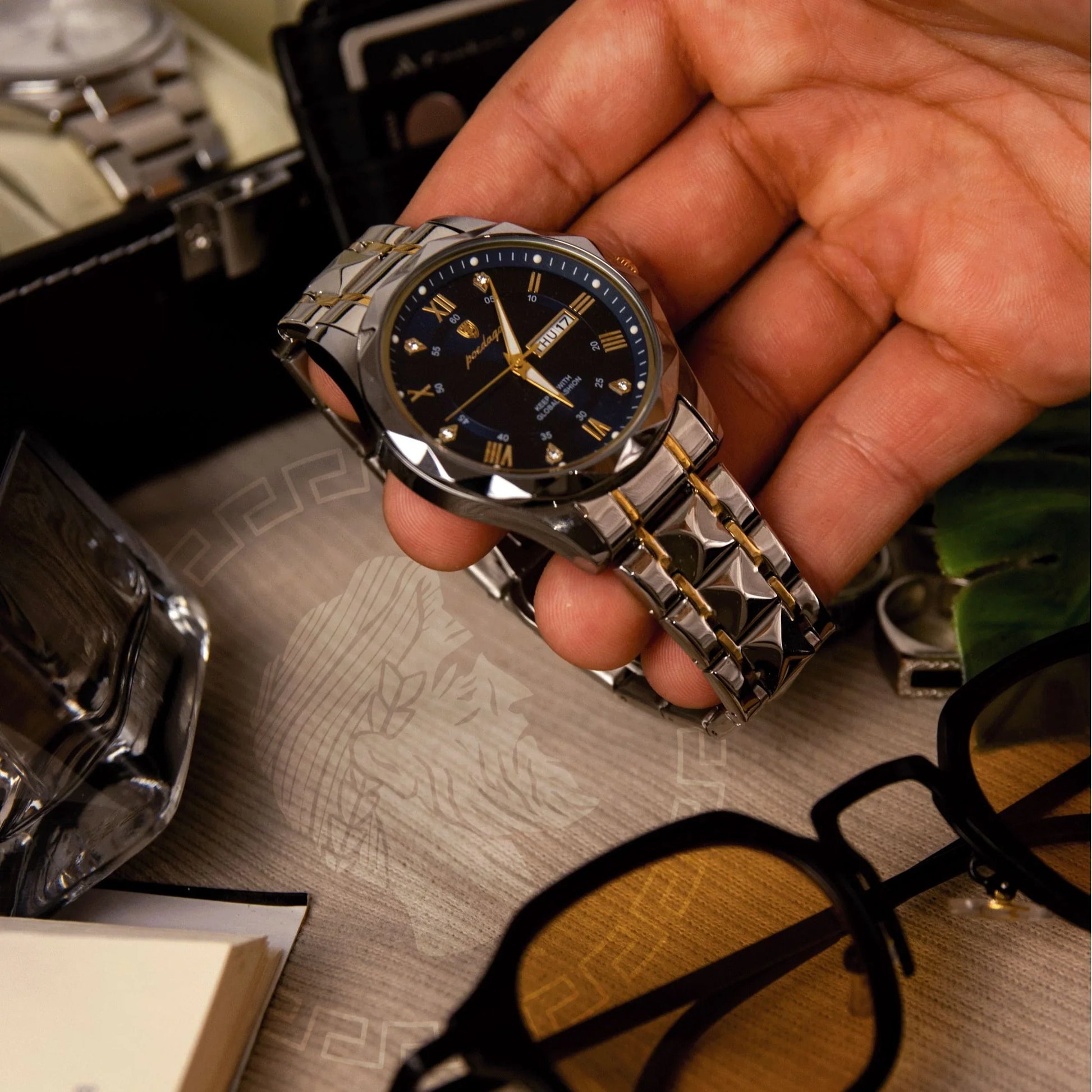 Hand holding Auretier men's steel luxury wristwatch with black dial, gold accents, and calendar